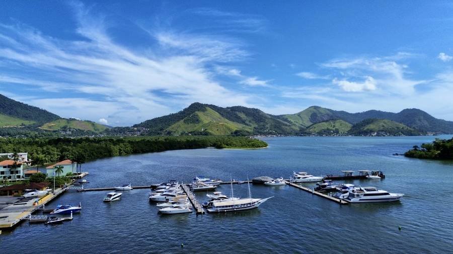 Vista aérea de marina com embarcações atracadas, cercada por montanhas — vistoria aérea NauticaFly